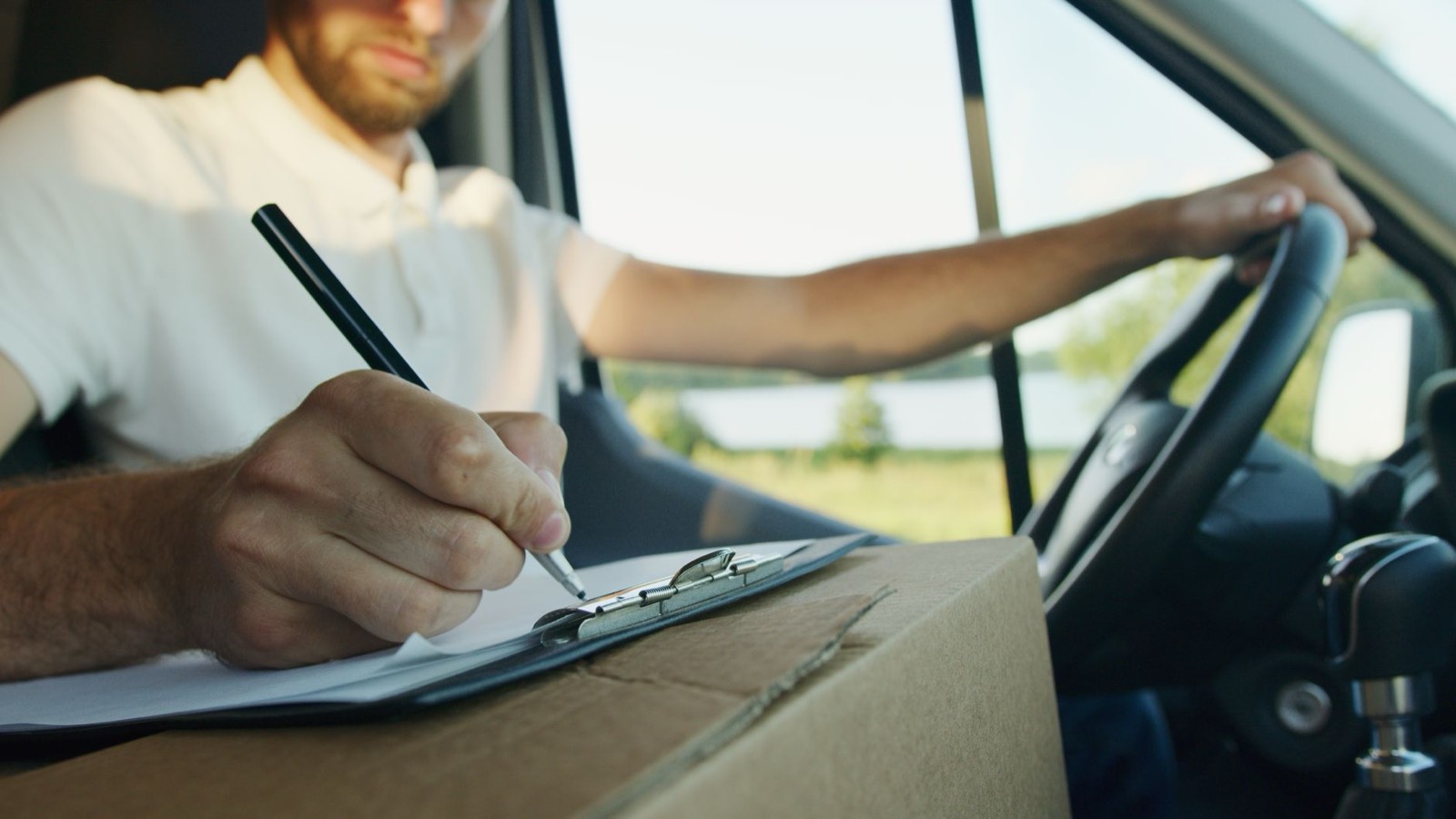 Électricien assis à l'arrière de sa camionnette, une tablette et des documents de chantier à la main