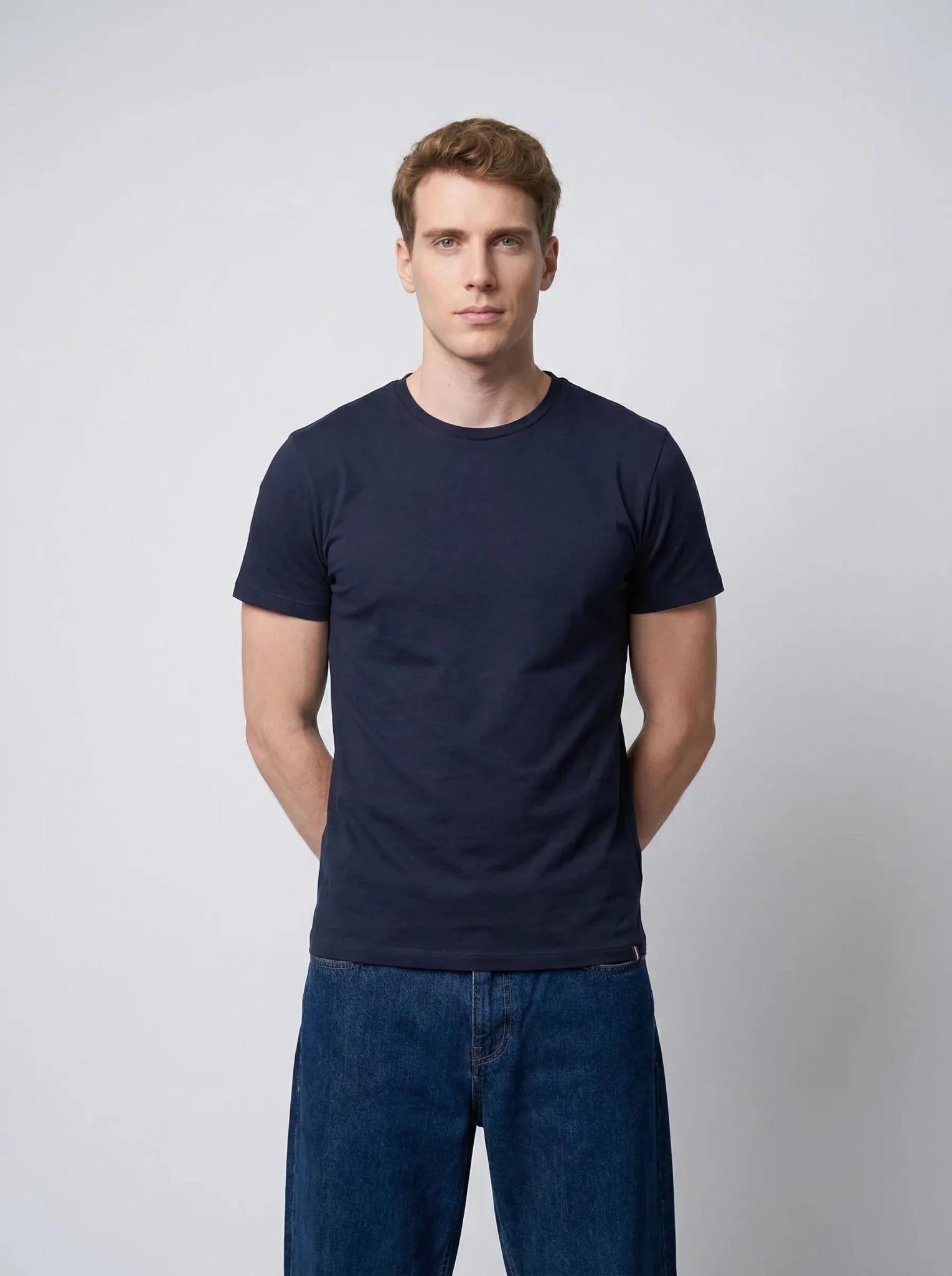 Homme portant un t-shirt bleu marine en coton, bras croisés derrière le dos