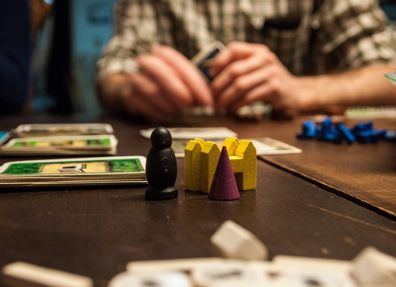 famille de quatre personnes jouant à un jeu de société autour d'une table, lumière chaude de salon