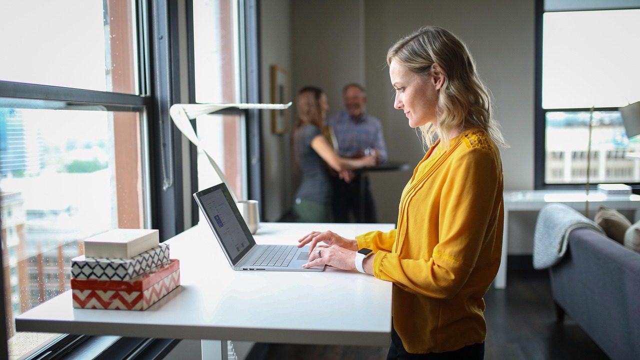 Personne qui se lève et s'étire à son bureau dans un espace de travail lumineux