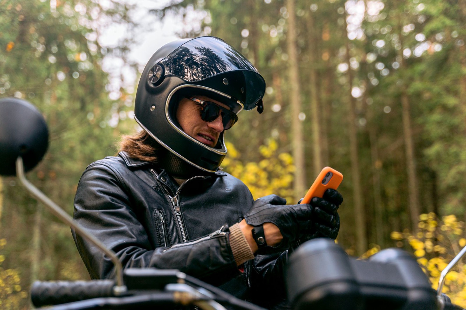 Smartphone fixé sur un tableau de bord, conducteur portant des gants de moto